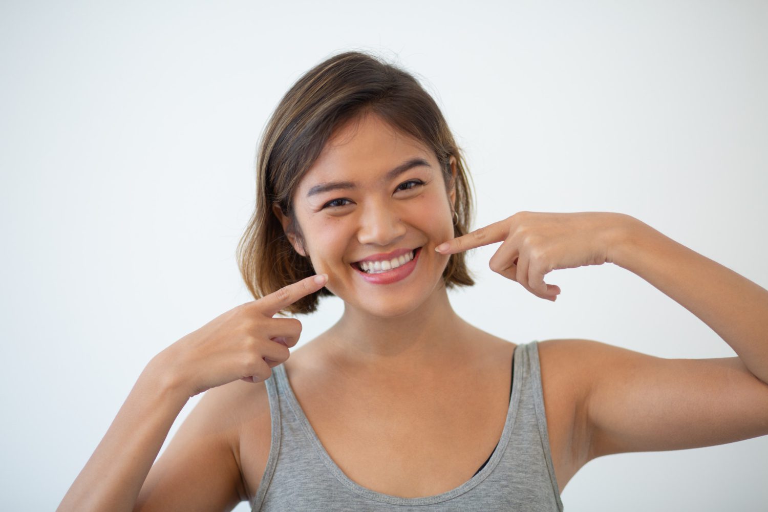 Smiling pretty Asian woman pointing at her teeth